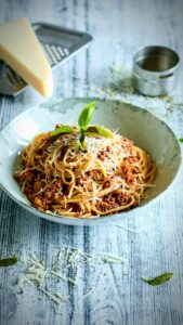 Josef Nemrava Instagram - 🍝”Boloňské špagety”

🥫😅Taky by se dalo říct trochu lepší špagety s kečupem a eidamem😅😅
Tak a rádoby odborníci na italskou kuchyni honem všichni do mne🤣🤣🤣

Jo já dělal zas dávku pro 25 lidí, tak se videa nezalekněte😅🙈

Ragú Bolognese:
🥩500g mletého hovězího masa
🫒3 PL olivového oleje a pak ještě na zakápnutí
🥕120g mrkve
🌱120g celeru
🌱2 řapíky řapíkatého celeru
🧅1 cibule
🧄3 stroužky česneku
🍷3 dcl červeného vína
🥫400 ml pasírovaných rajčat
🧂6 kuliček nového koření
🌱4 bobkové list
🌱oregana
🧂8 kuliček pepře
🧂Sůl
🎂Cukr na dochucení kdo má rád sladší omáčku

🍝Do hrnce si dáme rozpálit olivový olej a na něj dáme restovat na hrubo nastrouhanou mrkev a celer.
🍝Přidáme na drobno pokrájenou cibuli, řapíkatý celer a taky zarestujeme.
🍝Následně přidáme mleté maso osolíme a překvapivě zarestujeme.
🍝Přidáme nadrcený česnek, pasírovaná rajčata, osolíme, opepříme a zamícháme
🍝Směs zalijeme vínem, přidáme v sítku na koření, bobek nové koření, pepř, přiklopíme a dáme na 90 minut do trouby na 140 St.
🍝Před podáváním si vždy odebereme porci do pánve přidáme trochu vody z těstovin, špetku oregana, přistrouhneme parmazán, případně pro děti dosladíme a smícháme se špagetama.
🍝Na talíři pak ještě vydatně zastrouhneme parmazánem.

Dobrou chuť👍🍝