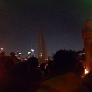 Julia Holter Instagram - from a @wawog_now event Jan 18: hundreds of Angelenos gathered for a vigil at Echo Park Lake to mourn and honor the lives of the writers, scholars, journalists, and poets among Gaza’s martyrs. This is an excerpt of Fariha Roisin reading “I Grant You Refuge” by Hiba Abu Nada (32, killed in her home in Khan Younis Oct 20 by Israeli airstrike)

Hiba Abu Nada (trans. Huda Fakhreddine)
1. I grant you refuge in invocation and prayer. I bless the neighborhood and the minaret to guard them from the rocket
from the moment it is a general’s command until it becomes a raid.
I grant you and the little ones refuge, the little ones who change the rocket’s course before it lands with their smiles.
2. I grant you and the little ones refuge, the little ones now asleep like chicks in a nest.
They don’t walk in their sleep toward dreams. They know death lurks outside the house.
Their mothers’ tears are now doves following them, trailing behind every coffin.
3. I grant the father refuge, the little ones’ father who holds the house upright when it tilts after the bombs. He implores the moment of death: “Have mercy. Spare me a little while. For their sake, I’ve learned to love my life. Grant them a death as beautiful as they are.”
4. I grant you refuge from hurt and death, refuge in the glory of our siege, here in the belly of the whale.
Our streets exalt God with every bomb. They pray for the mosques and the houses. And every time the bombing begins in the North, our supplications rise in the South.
5. I grant you refuge from hurt and suffering.
With words of sacred scripture I shield the oranges from the sting of phosphorous and the shades of cloud from the smog.
I grant you refuge in knowing that the dust will clear, and they who fell in love and died together will one day laugh.

A printed manifesto, collectively written by members of WAWOG’s Los Angeles chapter, was distributed to the crowd. Excerpts below:

WE ARE 100  DAYS IN AND STILL WE HAVE NOT ACHIEVED A CEASEFIRE.
JOURNALISTS, WRITERS, POETS, AND SCHOLARS ARE BEING TARGETED BECAUSE THEY ARE THE KEEPERS OF LIVING HISTORY.
WE DEMAND A PERMANENT CEASEFIRE, AN END TO ISRAEL’S SIEGE ON GAZA, AND AN END TO OCCUPATION NOW.