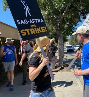 Kirsten Nelson Instagram - Day 1 & Day 73. We didn’t want a strike but we are not afraid of a fight. 
Back at Warner Bros. and man the picket line atmosphere has SKYROCKETED! 9am arrival & the lines were already packed (actors take that fucking calltime SERIOUSLY). Signs and tshirts needed to be restocked. Split the tent check-ins between gates for the Writers (Gate 4) and the Actors (Gate 2- freaking SMART!!). Stood with HUNDREDS if not a THOUSAND fellow laborers blowing whistles and cheering on the show of support from honking cars!! We’ve swollen the sidewalks around the studio to capacity!! God forbid we’re here another 73 days but our resolve is fierce and strong. Plus… I’ve got a new sign…

One day longer, one day stronger!
#SAGAFTRAstrike #WGAstrike #1u