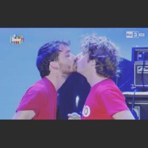 Lodovico Guenzi Instagram - Tutte le volte che due uomini si baciano in tv non riesco a non pensare a quante menate ci fecero otto anni. Non era sanremo, era il primo maggio. Ma per la regola che regge la televisione generalista - la tv è sempre almeno 30 anni in ritardo sul mondo e quando una cosa da scandalo in tv nel mondo reale ha finito di stupire - ci fecero un’infinità di storie. Nel 2015 il bacio tra uomini era già normalissimo nella vita vera, in tv OH MIO DIO. Avremmo dovuto avere sei coppie a baciarsi, non li fecero salire sul palco (vi prego risparmiatemi complottismi e colpevolismi social, sono passati otto anni e questa deriva di internet che confonde l’informazione con il gossip è insostenibile) quindi ci baciammo tra di noi. Poco dopo un assalto di giornali, indignazione, politici su di giri, il direttore artistico del primo maggio che mi bacio in bocca davanti a tutti per dimostrare che ci sosteneva (ora siamo amici, ma mi prese un po’ in contropiede allora, così, senza neanche invitarmi a cena…). 
Ora potete leggere questa cosa in maniera scema oppure intelligente. Quella scema è ORRORE CENSURA SCANDALO e altre stronzate. Quella intelligente è che io non so cosa sia successo allora, ma è evidente che adesso grazie al cielo un bacio fra uomini è difeso. E dovremmo smetterla di aver paura del progresso, che è quella cosa per cui con il tempo chi aveva un’idea retrograda la supera, e per questo c’è da essere felici, non condannare la gente. Anche perché, credetemi, molte delle idee corrette e inattaccabili che sfoggiate ora, sentendovi perfetti, fra qualche anno scopriremo essere limitate, discriminanti, retrograde. Questo paese è peggiorato in molte cose, ma vedere due uomini che si baciano in tv, sempre più spesso, e accorgersi che la gente vede la cosa normale come in effetti è, è un piccolo passo avanti, a cui brindare. E comunque, rega, manco la lingua… 
#kiss #bacio #libertà