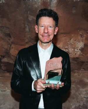Lyle Lovett Instagram - We’re counting down the days until Lyle Lovett returns for an incredible 25th appearance on July 9! A 2018 Red Rocks Hall of Fame inductee, Lyle first stepped onto our stage (and into our hearts) in 1990 before returning to headline with his Large Band in 1992, establishing himself as a Red Rocks regular ever since. Stroll down memory lane:

🤵  Playing his 13th show in 2007 – a co-headline with K.D. Lang
🎉  Backstage with one of his many his Piece of the Rock Awards in 2005
🎻 His Large Band got even larger in 2023, appearing with the Colorado Symphony
📆  See you in two weeks