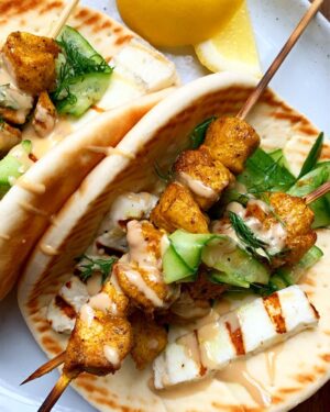 Megan Mitchell Instagram - This will forever be a favorite of mine. Chicken is tossed with cumin, turmeric, lemon and other spices then skewered and grilled until tender. It then gets stuffed into a fluffy pita with halloumi, a simple cucumber salad, fresh dill and drizzled with tahini. ⁣
⁣
You can sub in feta for the halloumi and use a grill pan or bake the chicken at 400F for 15-17 minutes or until cooked through. Recipe linked in bio