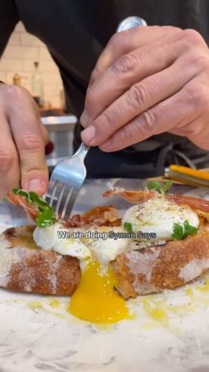 Michael Symon Instagram - This is how I poach my eggs… you don’t have to be intimidated to try this method!!!.. it can be super simple… served on sourdough with crispy prosciutto, breakfast in 90 seconds never tasted better! 🥓🥚 

Poached Egg
with crispy prosciutto 

Serves 1

2 large eggs
2 slice of grilled sourdough bread
2 pieces of Prosciutto 
1 tbl Champagne vinegar
Salt & pepper
Parmesan cheese to taste
Flat leaf parsley 

Bring 3 qts of water to a slight boil. Add a few splashes of vinegar and salt to boiling water.
Crack each egg into a separate small dish. Swirl the water in the pot to create a whirlpool effect and add eggs one at a time to the pot. Continue to stir in a circular motion. Cook 90 seconds for a runny yolk, eggs can be simmered longer for a firmer yolk.
Crisp the prosciutto in a hot frying pan, approximately 1 minute per side.
Serve over grilled bread and top with crispy prosciutto, parmesan cheese, salt/pepper, flat leaf parsley and drizzle of extra virgin olive oil. Enjoy.