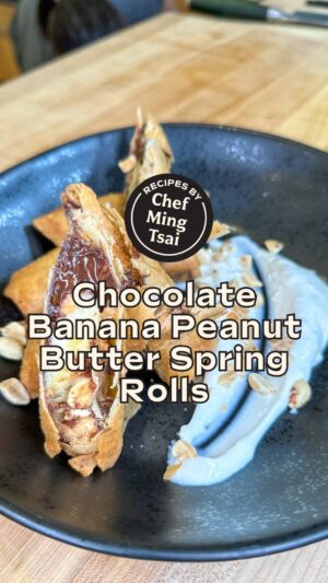 Ming Tsai Instagram - Spring rolls for dessert? Your wish is Chef @mingtsai’s command! 👨‍🍳⁠
⁠
INGREDIENTS⁠
1 package Lumpia Wrappers, defrosted ahead of time so you can peel them easily⁠
2 Bananas, peeled and cut into eighths (cut banana into quarters lengthwise, then cut the quarters in half widthwise)⁠
1 bar 70% dark chocolate, finely chopped⁠
About 1 cup peanut butter⁠
1/2 cup salted peanuts, roughly chopped⁠
Vegetable Oil for frying ⁠
Suggested garnishes: ice cream, chocolate sauce, yogurt ⁠
⁠
INSTRUCTIONS⁠
1) Place lumpia wrapper on a dry cutting board with the point of one of the corners facing towards you (so it looks like a baseball diamond from above). ⁠
2) Spread 1 tbsp peanut butter widthwise 1 inch from the bottom point of the wrapper. ⁠
3) Place a banana spear on top of the peanut butter, sprinkle with chocolate, and top with 1/2 tbsp peanuts. ⁠
4) Roll your spring roll: Bring the bottom point closest to you (home plate) to the pitcher’s mound, and roll it once on itself. Egg wash the remaining edges. Fold first and third base in towards the middle of the roll and roll it the rest of the way. Letting it rest on the seam. ⁠
5) In a heavy saucepan or cast iron pot, heat vegetable oil to 375 degrees Fahrenheit. Gently place spring rolls in oil, about 5 at a time (do not overcrowd your pot). Cook 4-5 minutes until golden, brown, and delicious (GBD). ⁠
6) Remove from oil and place on a plate lined with paper towels to drain. ⁠
7) Serve hot with a thick yogurt, ice cream, or chocolate sauce. Top with more chopped peanuts. ENJOY! ⁠

🌟 Make sure to SAVE this recipe to make later! 🌟

#springroll #asiandessert #dessertrecipe