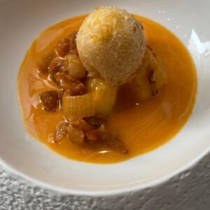 Pepe Rodríguez Instagram - Cachelos con chorizo, huevo frito y ajada 

@hoyhuevo 

🥔Ingredientes para los cachelos: 
300gr de patatas cortadas en cachelos 
Agua 
Laurel 
Sal

Elaboración:
Poner a cocer los cachelos en agua con sal y laurel. Una vez estén cocidos, reservar.

🧅Ingredientes para la cebolla con chorizo:
80 gr de chorizo fresco picado 
150gr de cebolla picada 
60gr de aceite de oliva virgen extra 

Elaboración:
Pochar la cebolla con el aceite y añadir el chorizo picado. Rehogar un minuto y reservar.

🥚Ingredientes fritura huevo:
1 huevo 
350gr de harina 
360gr de trisol 
Una pizca de sal y azúcar 
12gr de levadura fresca 
600gr de agua tibia 

Elaboración del huevo frito:
Deshacer la levadura en el agua tibia.
Añadir el resto de ingredientes y dejar que suba de volumen. Reservar.

🧄Ingredientes ajada:
300gr de oliva común 
50gr de oliva virgen extra 
1 cebolla en juliana 
Laurel
Tomillo 
1 cabeza de ajos 
Clavos y pimienta negra 
500gr de caldo de pollo 
15gr de pimentón dulce 
5gr de vinagre de jerez 

Elaboración ajada:
Pochar en los aceites la cebolla con los aromáticos y el ajo.  Cuando esté muy pochado añadimos el pimentón y el vinagre y reservamos.
Colamos y mezclamos con el caldo de pollo en un robot para emulsionarlo.

Emplatado : 
Mezclamos la cebolla con el chorizo y las patatas, ponemos a punto de sal y colocamos en un aro. Sacamos la yema de huevo, pasamos por la masa de fritura y freímos, de esta manera quedará crujiente por fuera y cremosa por dentro. Colocamos encima de las patatas y añadimos alrededor la salsa de ajada.

#MasterDelHuevo