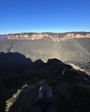 Rae Johnston Instagram - The sun and moon sharing the sky, sandstone paths, grass trees, huge ancient cliff faces, and that beautiful river flowing in the deep valley below 🤎 

Today’s walk on Wiradjuri, Darug & Gundungurra Country - making the most of the clear skies while they last, looking wet and below freezing next week! 

#bluemountains #rigbyhill #piercespass #wiradjuricountry #darugcountry #gundungurracountry