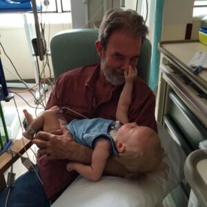 Rob Delaney Instagram - Today would’ve been my dad Bob’s 75th birthday. He died last October of leukemia. I love him and I miss him and I still talk to him from time to time. Here’s a picture of him holding my son Henry, who died in 2018. My dad took very good care of Henry and his brothers too. I am so grateful I could care for my dad over the 2 years he was sick. Look at the love in this photo. See you around, guys.