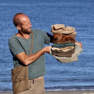 Rob Greenfield Instagram - This is my entire wardrobe.

18 items – 4 shirts, 2 shorts, 1 pants, long underwear top and bottom, shawl, hat, cowl, wool booties, moccasins, 3 pairs of socks and a bag.

All hand made. All natural fiber. All naturally dyed.

Just as a deer could fall to the forest floor and return to the soil, so could I in these natural clothes. 

Wool, linen, cotton, deer leather and sinew and wood are the materials.
Black walnut, indigo, weld, turmeric and iron rust are the dyes.

It’s been a year since the first item was completed and 3 months since I shedded my last clothing from my former life.

I can’t say it’s all been easy. Both shorts have ripped in the butt area and the soles of the shoes have already worn through. Many of the clothes were made too small and seams are breaking where they are too tight. They aren’t the most comfortable clothes I’ve ever worn… But this is all part of the experiment in reconnecting with Earth. I am elated for the trials and tribulations of it all. To live in harmony with Earth is to repair, to rethink and to reconstruct my possessions, my mind and all of my relations.

My wardrobe is not fully complete, and I am calling out to the community for a few items!

To keep my nose and head from burning I am seeking a sun hat. Felted wool or woven plants are my ideal materials, but I’m exploring the world of covering my head with the gifts of Earth!

For warmth, I am seeking a wool sweater. Is there anyone with a homemade, natural fiber and naturally dyed sweater I could buy or borrow until this fall? Or someone who could make one this month? I can source and provide the local yarn!

For soles for my shoes, I am seeking thick, naturally tanned leather as well as some sinew. I only need small chunks, so scraps could do. I’d also love to hear any experiences with long-lasting natural soles!

To make padding for my backpack straps, I need some wool roving.

I’m happy to purchase, trade, or receive as gifts for those who operate in a non-linear, more circular giving system like I do!

Love,
Robin

Photo by Greg Sachs @sachsquatchinthewild
Learn all about my journey to natural clothes at robingreenfield.org/clothes