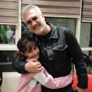 Tamer Karadağlı Instagram - Bu fotoğrafta  gözlerinden sevgi ve umut fışkıran tatlı kızın adı Selda Pehlivan.11 yaşında.2 gün önce “SERHAT” dizisi oyuncularıyla gittiğimiz Antakya’da tanıştık. Ailesiyle birlikte yaşadığı büyük travmaya rağmen halâ yüzü gülüyor. Çadırkent’e gittiğimde beni ilk görenlerden biriydi Selda. Sonra diğer çocuklar ve vatandaşlar benim yanıma fotoğraf çektirmek için geldiğinde, Selda o karışıklığın içinde kaybolmaya başladı. Tam yanımdan giderken “Lütfen beni unutmayın!” dedi. Yüzü halâ gülüyordu ve kalabalıkta beni izledi. Ama o kalabalığa girmedi. Daha sonra depremzede vatandaşlarımızla görüştükten sonra oradaki yetkililer bize çay ikram etti. Ben de fırsattan istifade edip Selda’yı ve ailesini çağırtıp onlarla oturup konuştum. Selda’nın babası Mehmet Pehlivan Sağlık Bakanlığı personeli. Evleri yıkılmamış ama evlerinde kalamıyorlar. Belki tayini Antalya’ya yada Mersin’e çıkar. Neresi olursa olsun onlarla irtibatım kesilmeyecek. Selda çok iyi bir öğrenciymiş. 5.sınıfa gidiyor. Onun iyi bir eğitim alması için elimden geleni yapacağım. Deprem bölgelerine benim 3. gidişim. Gidişlerimiz çok önemli. Yıllarca seyrettikleri oyuncuları gördükleri zaman yüzleri gülüp yaşadıkları acıları bir an için unutabiliyorlarsa ne mutlu bize. İnsanların ruhuna, gönlüne dokunmak önemlidir. Ama daha önemlisi birilerinin hayatına dokunmaktır. Ben deprem bölgesinden döndüm. Hayatın koşuşturması içindeyim yine. Hayat bir şekilde devam ediyor. En yakın zamanda yine depremden zarar gören yerlere gidip üzerime ne düşüyorsa yapacağım. Etrafımı kalabalık sararken Selda bana “Lütfen beni unutmayın!” demişti.. SENİ UNUTMADIM SELDA PEHLİVAN.. Çadır numarası 62..Ve sana SÖZ VERİYORUM seni hiç unutmayacağım..