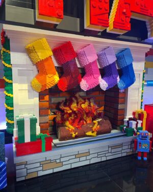 Amy Corbett Instagram - Behind the scenes photodump from @legomastersfox Celeb Holiday Bricktacular 🎄🎅🌟
Have you watched yet? If not, what are you waiting for??? Find it on Hulu 🤩Also…how awesome is all the brick built scenery on set!?! Thought you might like a closer look 🙌
📸 Getting my elf on - comfy slippers and clipped up curls 😂
📸 Brickbuilt fireplace 
📸This teddy bear was a personal fave 
📸Beautifully crafted sleigh 
📸Brickmaster having a blast on set
📸Family photos on the mantelpiece 😂
.
.
.
#legomasters #legomastersfox #legomastersusa #lego #legobuild #holidaybricktacular #celeb #build #play #legobuilders #afol #christmas #christmasspecial #holidayspecial