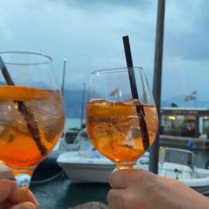 Angela Finger-Erben Instagram - 1. Ungeschminkt und 2. mit Sonnen gebleichten Haaren habe ich 3. den schönsten Ausblick auf den 4. Gardasee mit einem 5. leckeren Getränk in der Hand! Drei Wochen Familie, jeden Tag Pasta, Erfrischung im See - das ist schee 💚🤍❤️ #vacation #holiday #family #lagodigarda #italy #pasta #prost Bikini und Sonnenbrille von @brunottiwomen #unbezahltewerbung