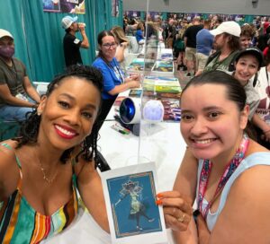 Anika Noni Rose Instagram - A wonderful day at @galaxyconraleigh! Thank you kind, beautiful people for all of the gifts you gave and the gifts you shared-sometimes all in one. 

Thank you to all of you who wore masks.

Thank you to every one of you who stopped by and shared your loving hearts with me. 

See you tomorrow!

Remember, if you have a mask, if you just want any to be cautious, if you THINK you don’t feel well, please mask up. If you KNOW you’re sick, consider staying home. These lungs can’t take a bout with the 🦠

Let’s keep each other safe out here! 
See you tomorrow for the panel!
💚👸🏽

1. @Raycayz, I got my sticker and I love it! Thank you!!
💚
2. Coloring from sweet baby Mila, and first friendship bracelet of the weekend 
💚
3. Gorgeous embroidery frog necklace from @natsnostalgicstitches
💚
4. Amazing Tiana art by @flocolores
💚
5. Some more gorgeous art, by sweet @artbyannae . Thank you for your beautiful talent and huge heart🥰

Thank all of you for a beautiful day!

Hair I love by @indiamhammond 
Onesie by @martinesdream 

#galaxyconraleigh #galxycon #princessTiana