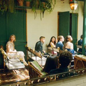 Barton Cowperthwaite Instagram - We were married in the Solarium next to the Piano Bar at the Hotel Chelsea. Choosing the Chelsea was an easy decision. It’s iconic, filled with art and history. I grew up on 22nd between 5th and 6th, and remember it in its late 90’s crumbling glory. The Solarium, small and perfect for our 35 guests, has a beautiful skylight running the length of the room. Decorated with plants and greenery, it was perfect as it was, requiring minimal decoration.

Our best friend Sammy (Bart’s best friend since birth) who knows us as individuals and as a couple better than anyone else, officiated the ceremony. It felt comfortable, relaxed, and unfussy. Our violinist played as we each walked down the aisle with our parents. The three of us stood in front of an arch I constructed from wooden dowels, tissue paper flowers from Etsy, Velcro, and hot glue. We were flanked by two bunches of my favorite Allium flowers. We each took a long moment to take in the space before our vows. We wanted to be as present as possible. 

After the ceremony, we had a champagne toast, and Bart’s brothers each said a few words. Our guests stayed for a cocktail hour while we left to do photos in our room. We left the Hotel Chelsea and went to the West Village with our photographers. Standing on a corner next to a tipped-over trash can for 15 minutes, trying to hail a cab, we were met with honks and cheers. It was a quintessential New York moment, a reminder that the city stops for no one.

We walked around the West Village, taking photos at all our favorite neighborhood spots. We stopped by Grove Apothecary to see our pharmacists, who have always taken such good care of us. We visited the Jane laundromat, where Bart has made friends with everyone who works there. We were all heartbroken when he got sick, but no one was as crushed as our friends at the laundromat. We dropped in at Casa Magazines, where Bart buys copies of the magazines he’s published in. This community is a part of our everyday lives. They’ve made our New York City feel like a close knit small town. Their kindness and care got us to the other side of a terrifying time, and we wanted to share a piece of the other side with them.