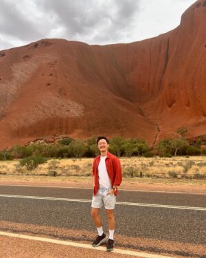 Benjamin Law Instagram - 24 HOURS IN ULUṞU

Shot this lil’ segment in beautiful Aṉangu Country after a rare evening of rain. It meant we could see the true black shade of the monolith under its red rust foundation, and how freshwater gathers at the base of the structure – which is taller than the Eiffel Tower, more ancient than the first dinosaurs and runs another 2.5km underneath.

Thanks to Uncle Sammy Wilson – son of Paddy Uluṟu! – for welcoming and handpicking bush tomatoes for us (an unexpectedly perfect mix of tomato and banana), and this dream team crew of the two Dans, Pariss, Bruno, Sarah and Toby. 

And, of course, icon Julia Zemiro who can do no wrong and for whom I would walk directly into peak hour traffic with my eyes closed if she asked. 

On yr TVs soon. Palya, peeps. ✌🏿✌️✌🏼