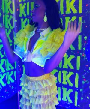 Dimitri Nana-Côté Instagram - LOTS of fun at @rendezvousdeladrag this weekend💕🌟 The first Quebec/Francophone drag convention went amazing!!

Thanks to everyone who came to my neon/paint booth and bought some merch!!🎨 

It was a challenge to make the neon/blue light effect functional!
Lots of paint, finding a way to isolate the ambient light, and picking outfits and makeups that would react differently under the light in my booth VS when I would walk around the convention center💡

Thanks to @thatboyfromthehub and @edward_jpeg for helping me set up my booth 💪🏾 & big merci to @theonlyrjjb for assisting me on day 1💛

Red/pink dress from my CDR1 package by @_thesukidoll & yellow outfit base from @gisele_lullaby 👗💃