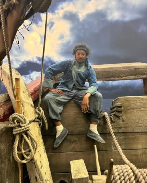 Samba Schutte Instagram - Today’s (Our) Flag (Means Death) Day, and many of you have asked for deets on my character Roach in Season 2🪳 Here you are🏴‍☠️ 
Details on the costumes during fittings and after weathering and aging. It was great collaborating with Costume Designer Gypsy and being able to implement my own backstory. For the Red Flag fit I wanted him to have a headband because a chef never gets hairs on his meals. Unless it’s on the menu, or you’re serving the British👨🏾‍🍳
For his new fit, Roach got to have more jewelry this season because he became a better pirate. I chose 3 rings. The Lion to symbolize the Atlas Mountains where he hails from. The 2 headed Snake, because you have to always watch your back as a pirate. And a Celtic looking ring, because Roach has a tender spot. Like with his mother’s scarf. And of course his talisman necklace that he always wears, with every costume🪬At first it was gonna be a long sleeve shirt, but Jenkins wanted me to show off my sexy dessert making arms. Rightly so…..💪🏾
On his belt he had meat hooks, his cleaver as a weapon and of course, a wooden spoon for self defense🥄
I’ve never worn Doc Martens before and let me tell you, I don’t know how people smaller than me do it, those things weigh a ton each! Now imagine running on the beach in them👀
More deets in stories but I loved every minute of dressing up as and playing this chaotic dude🫶 
#ourfladmeansdeath #ofmd #ofmdseason2 #roach #cosplay #bts