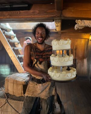 Samba Schutte Instagram - Today’s (Our) Flag (Means Death) Day, and many of you have asked for deets on my character Roach in Season 2🪳 Here you are🏴‍☠️ 
Details on the costumes during fittings and after weathering and aging. It was great collaborating with Costume Designer Gypsy and being able to implement my own backstory. For the Red Flag fit I wanted him to have a headband because a chef never gets hairs on his meals. Unless it’s on the menu, or you’re serving the British👨🏾‍🍳
For his new fit, Roach got to have more jewelry this season because he became a better pirate. I chose 3 rings. The Lion to symbolize the Atlas Mountains where he hails from. The 2 headed Snake, because you have to always watch your back as a pirate. And a Celtic looking ring, because Roach has a tender spot. Like with his mother’s scarf. And of course his talisman necklace that he always wears, with every costume🪬At first it was gonna be a long sleeve shirt, but Jenkins wanted me to show off my sexy dessert making arms. Rightly so…..💪🏾
On his belt he had meat hooks, his cleaver as a weapon and of course, a wooden spoon for self defense🥄
I’ve never worn Doc Martens before and let me tell you, I don’t know how people smaller than me do it, those things weigh a ton each! Now imagine running on the beach in them👀
More deets in stories but I loved every minute of dressing up as and playing this chaotic dude🫶 
#ourfladmeansdeath #ofmd #ofmdseason2 #roach #cosplay #bts