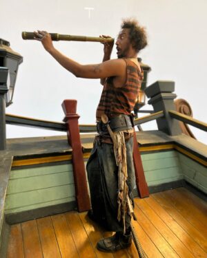 Samba Schutte Instagram - Today’s (Our) Flag (Means Death) Day, and many of you have asked for deets on my character Roach in Season 2🪳 Here you are🏴‍☠️ 
Details on the costumes during fittings and after weathering and aging. It was great collaborating with Costume Designer Gypsy and being able to implement my own backstory. For the Red Flag fit I wanted him to have a headband because a chef never gets hairs on his meals. Unless it’s on the menu, or you’re serving the British👨🏾‍🍳
For his new fit, Roach got to have more jewelry this season because he became a better pirate. I chose 3 rings. The Lion to symbolize the Atlas Mountains where he hails from. The 2 headed Snake, because you have to always watch your back as a pirate. And a Celtic looking ring, because Roach has a tender spot. Like with his mother’s scarf. And of course his talisman necklace that he always wears, with every costume🪬At first it was gonna be a long sleeve shirt, but Jenkins wanted me to show off my sexy dessert making arms. Rightly so…..💪🏾
On his belt he had meat hooks, his cleaver as a weapon and of course, a wooden spoon for self defense🥄
I’ve never worn Doc Martens before and let me tell you, I don’t know how people smaller than me do it, those things weigh a ton each! Now imagine running on the beach in them👀
More deets in stories but I loved every minute of dressing up as and playing this chaotic dude🫶 
#ourfladmeansdeath #ofmd #ofmdseason2 #roach #cosplay #bts