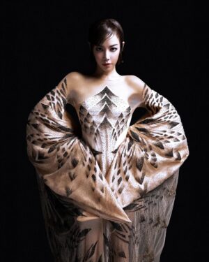 Fiona Xie Instagram - The Alchemy of @irisvanherpen @voguesingapore 

“I find beauty in the continual shaping of chaos which embodies the primordial power of nature’s performance,” Iris van Herpen once said—words that illuminated my understanding of her work at the nexus of ancient alchemy and @cern physics.

Her liminality is her genius. “I see technology as a tool to express the handwork better,” she explains, dissolving false binaries. When her kinetic structures breathe with the wearer, we witness her core philosophy: “Movement is my constant inspiration. Our human body is in continuous motion, as is everything around us.”

These undulating architectures manifest what philosopher Merleau-Ponty called “the flesh of the world”—the profound interconnectedness between perceiver and perceived. Her approach transforms rigid materials into liquid motion, embodying Bachelard’s insight that “matter is the unconsciousness of form.”

I remember showing my friend @grimes in that “Dune of Souls” creation at the met gala whispering “It would be a dream to wear these.” Then @voguesingapore @nat_tasha ‘s call came—Iris would dress me for the @artsciencemuseumsg retrospective. I swooned like a teenager locked lips in her first kiss. Manifestation is real. 

“Fashion is an expression of the zeitgeist, while couture is an expression of eternal beauty.” These words resonated as I stood transfixed clad in her “Architectonics” collection—embodying what Rilke meant by “living the questions” about our relationship with technology, philosophy, architecture, music, nature, and our bodies.

Draped in her vision, I understood: Iris van Herpen doesn’t design clothing. She designs portals to possibility itself.​​​​​​​​​​​​​​​​

Be transcended at @artsciencemuseumsg 
#IrisVanHerpen #ArtAndFashion #Metamorphosis​​​​​​​​​​​​​​​​ #Vogue