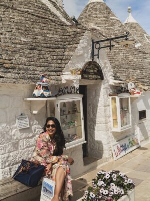 Rebecca Roy Instagram - 📍Alberobello in one magical morning!

This UNESCO World Heritage town in Puglia is famous for its Trulli — cone-roofed houses built entirely without mortar. These stone homes date back to the 14th century and were once designed to be easily dismantled to avoid taxes!

In just a few hours, we:
• Wandered through quiet Trulli lanes under the morning moon
• Learned about their fascinating architecture and history
• Explored charming local shops inside the Trulli
• Tried local wines, fig jams & olive oil
• Soaked in that golden morning light that made the whole town glow

Tip: We stayed in an actual Trulli at @tipicoresortalbergo — and highly recommend spending a night (or two!) here instead of doing a day trip.
Waking up early and catching the peaceful streets before the crowds arrive? 100% worth it.

Travel by @gtholidays.in 

All content is self shot 

#Alberobello #TrulliExperience #PugliaTravel #UNESCOWorldHeritage #coupletravel #ItalyHiddenGems #TipicoResort #TrulliStay #SlowTravelEurope #AlberobelloTips #chennaiinfluencer