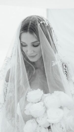 Delta Goodrem Instagram - The Making of @deltagoodrem’s Wedding Gown | A long-sleeved French tulle ball gown featuring a sweeping off-the-shoulder neckline, scalloped and lattice detailing, and a statement pleated skirt with a cascading cathedral train. The gown is complemented with an embroidered Italian tulle veil.