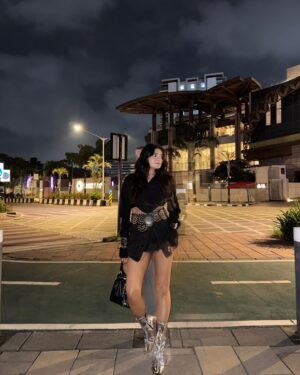 Simran D Sharma Instagram - City lights, silver boots, and no rules…. 🪩
.
.
#FashionInspo #OOTD #StyleGoals #TrendAlert #StreetStyle #InstaFashion #BootGameStrong #StatementLook #AllBlackFit #SkirtStyle #BoldFashion #ChicAndSassy