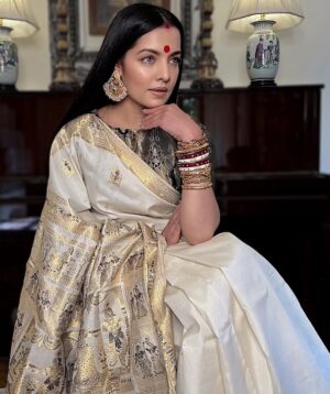Celina Jaitly Instagram - #durgapujo From Bankura To My Heart, How My Mother’s Swarnachari Became My Source of Courage

As #bodhon takes place when your face is unveiled, I will find you again appearing in my life as if you never left, as if the teacup is still warm & you left to get some mishti.

Maa ami tumader jonney ek borsho thikey dariye aachi… etokhun golpo acchey.

Sometimes I find myself standing in a world that feels like it has been built to break me, trying to hold on all alone in a foreign land where nothing feels like home anymore. But with Shashthi I realise that no matter where I am everything is made from the dust beneath your divine feet decorated with alta & adorned with payel.

Home is always when you come, home is always when I hear the rustle of your saree, smell the perfume of the dhuna that follows you & the jasmine in your hair.

This #shashti I draped a Swarnachari #baluchari saree gold & ivory adorned with woven tales of Krishna Leela. It was bought by my late beloved mother from #bankura when I turned 18 years old. I do not understand kāno pori noi why I never wore it until today.

It was meant for me a blessing from my mother who collected sarees with so much love since I turned 16 on her Fauji husband’s salary & her own modest teacher’s salary so that I would shine on festivals so that I would always find her love woven around me.

To find the strength for śṛṅgār & to adorn myself in my late mother’s gift feels like a personal victory over unbearable pain life sometimes puts you through.

Through this I realise that offering my obeisance to Maa has shown me I can overcome anything. So can you, for Maa always blesses, always protects.
This is a Shashthi of many personal victories & a lot of pain to navigate. Yet today I stand wrapped in my mother’s blessing whispering to you Maa bring back the warmth of home bring back the strength of my ancestors bring back the hope that rises with your arrival. Bring it back not just to me but to anyone reading my prayers to you, anyone navigating circumstances that feel treacherous.

Maa ami tomake pranam kori shokti roopini Maa shob kichhu’r majhe tumi aacho…
#festivalsofindia #pujo #swarnachari #saree #celinajaitly