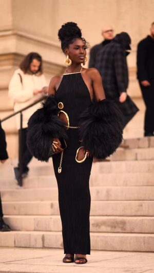 Jodie Turner-Smith Instagram - TURNER ON.   @JodieSmith arriving to the @Schiaparelli Spring/Summer 2026 Haute Couture Show at the @PetitPalais_Musee in Paris.  Jodie wears a long dress in black viscose knit with tree bark effect, embellished with irregular cut-outs trimmed with gold metal and a gold jewel chain at the back. Black fur embroidered jacket. Gold hoop earrings adorned with a delicate line of pavé diamonds. « Hand-in-hand » clutch bag in black velvet. Black leather heeled sandals decorated with a signature tape measure embroidery inspired by one of the House’s iconic codes.  Stylist @LuxuryLaw Video @SametGorgozfilms Music @BenBrunnemer  #Schiaparelli